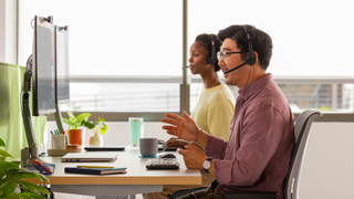 The new Logitech H570e Headset being used by a smiling man and woman. 