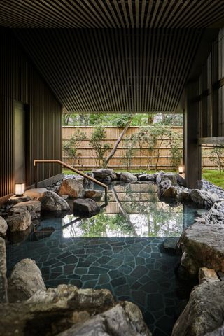 Onsen bath at the Aman spa in Kyoto, Japan with rocks and bamboo walls