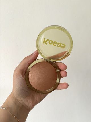 Mica Ricketts holding up the Kosas The Sun Show Baked Bronzer