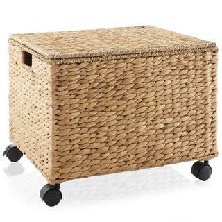 A light rattan woven storage basket with black plastic wheels