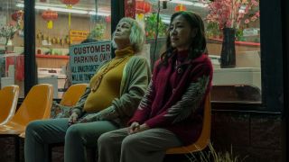 Jamie Lee Curtis and Michelle Yeoh sitting next to each other outside a laundromat