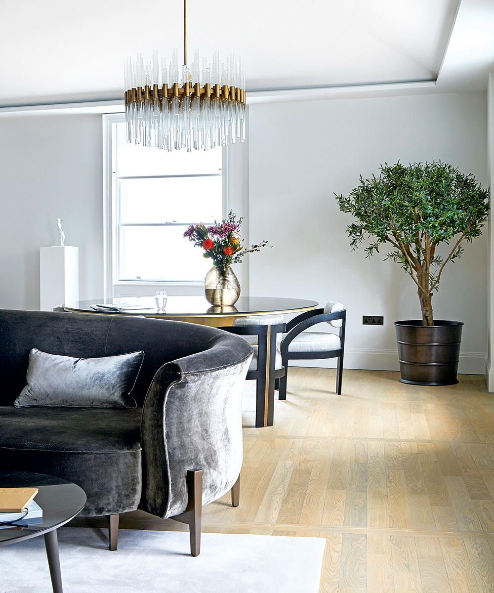 Small apartment living room ideas in a white scheme with gray velvet sofa and glass chandelier.