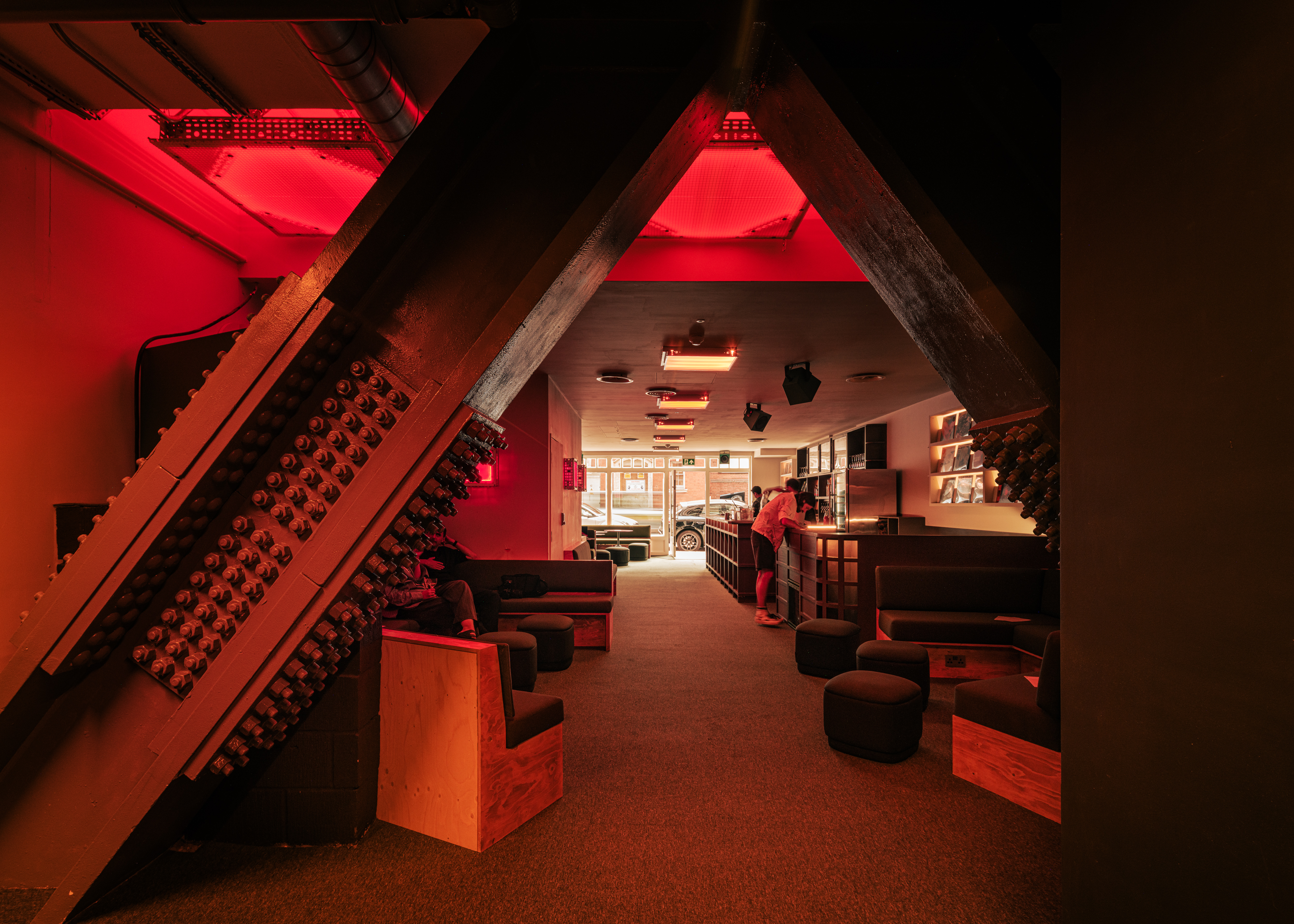 A dimly lit record store with red and orange neon light and spacecraft-informed interior design.