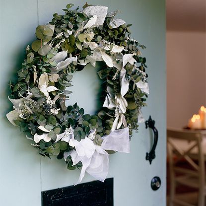 christmas wreath with white ribbon on blue door