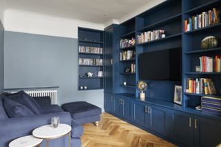 A living room with a dark blue tv unit and light blue couch