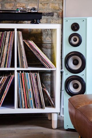 A white toned storage unit that houses records and a speaker