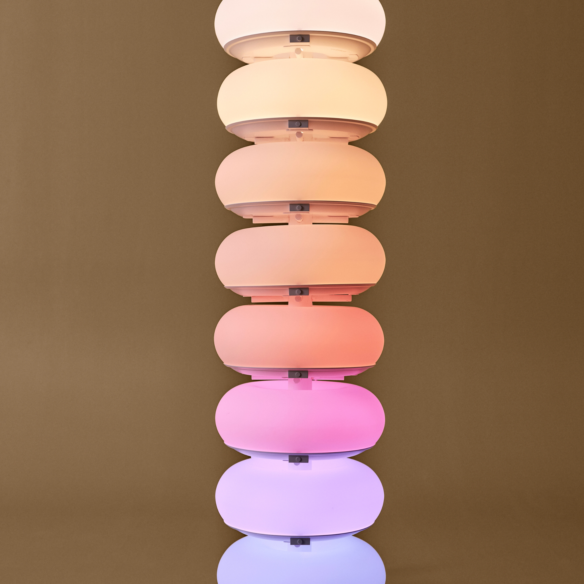 Doughnut lamps stacked on top of one another to show their range of colours. It fades from purple to pink, to orange, yellow and warm white.
