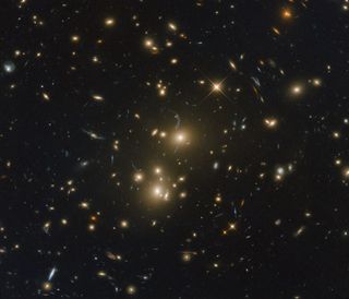 A Hubble image of galaxy cluster RXC J0232.2-4420 shows a star studded scene against the black backdrop of space.