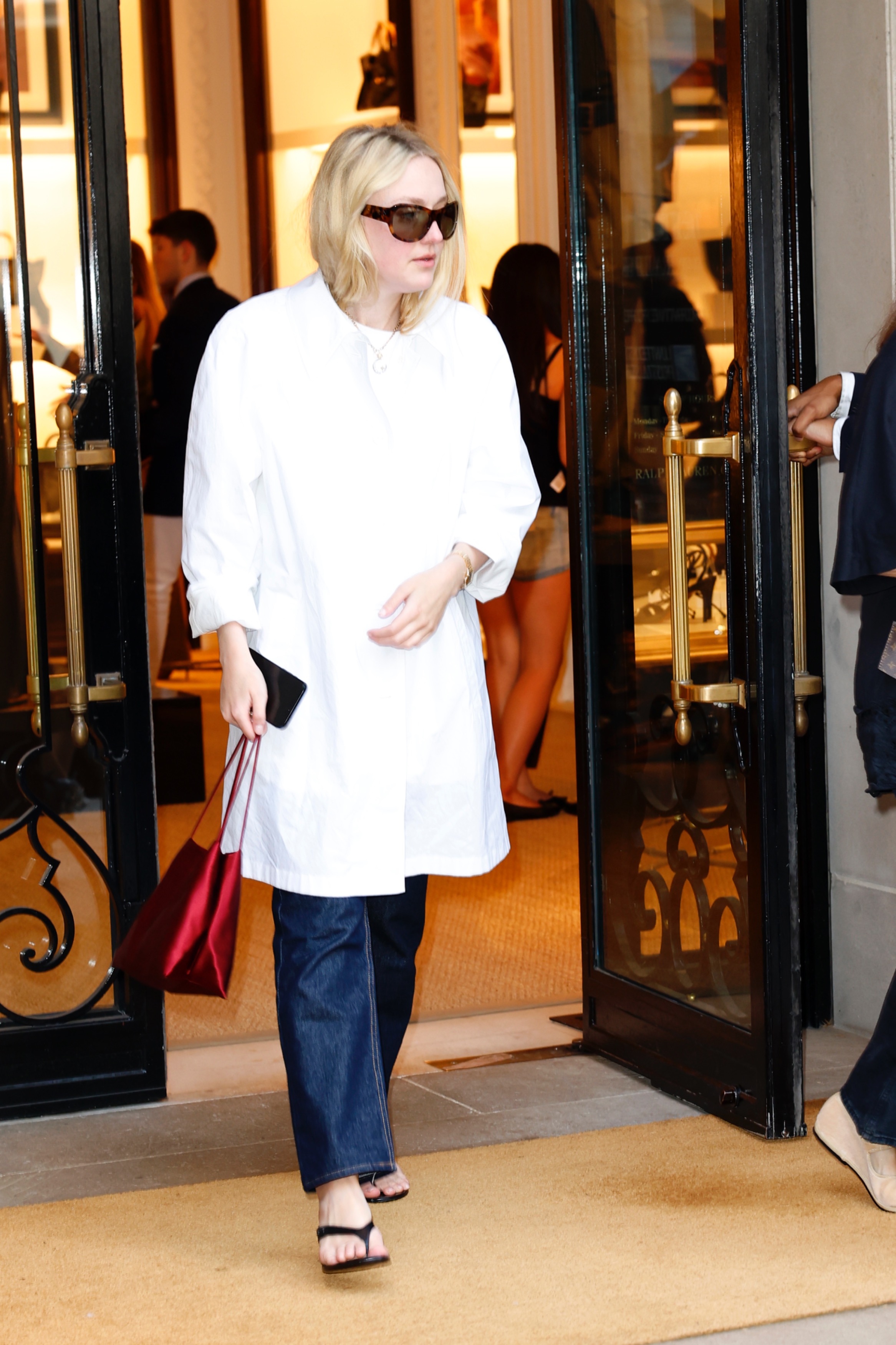 Dakota Fanning wears dark jeans, heeled flip flops, an oversize white shirt to Ralph Lauren