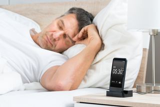 A man sleeps with his smartphone next to his bed.