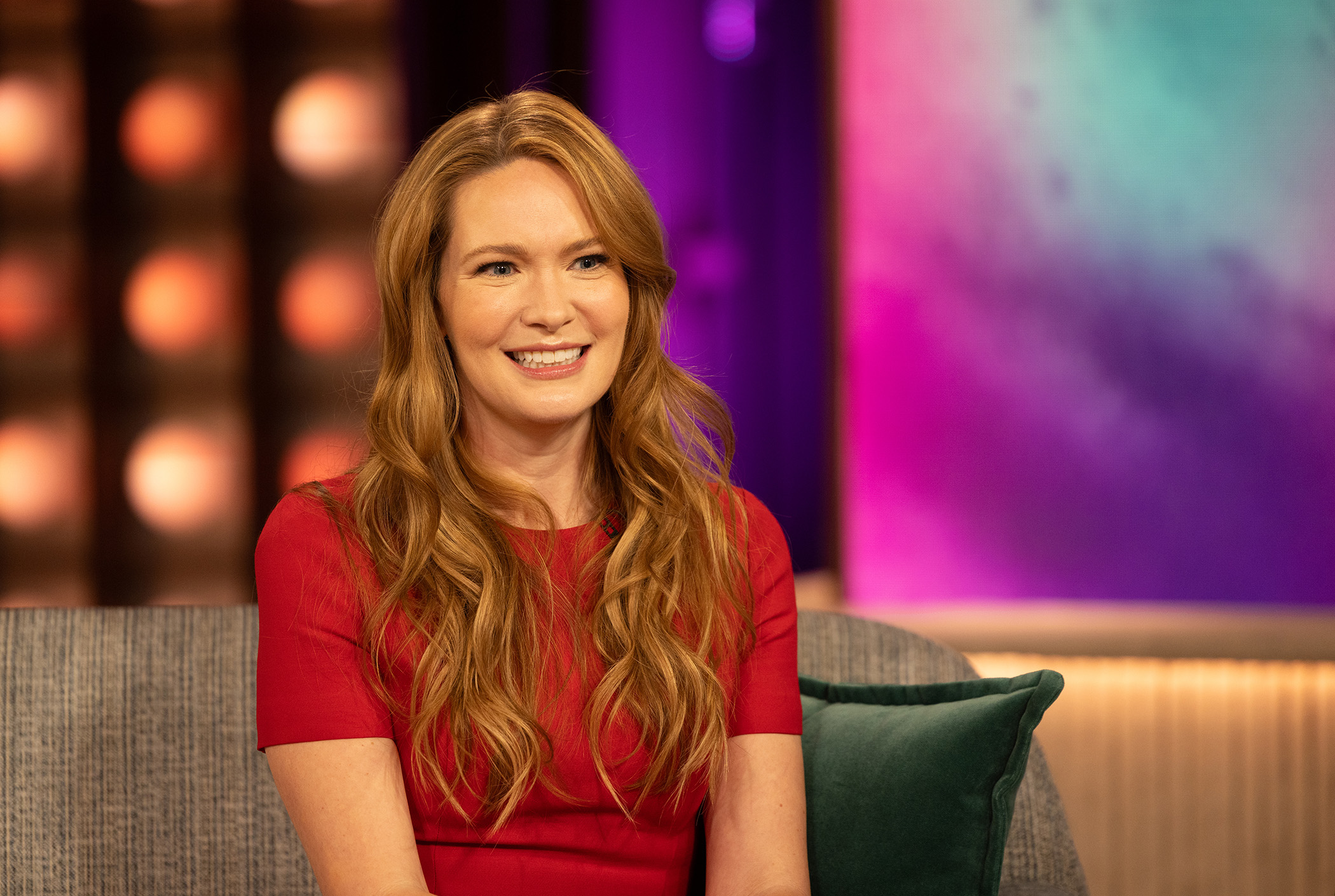 author sarah j maas wearing a red dress and smiling as she visits the kelly clarkson show