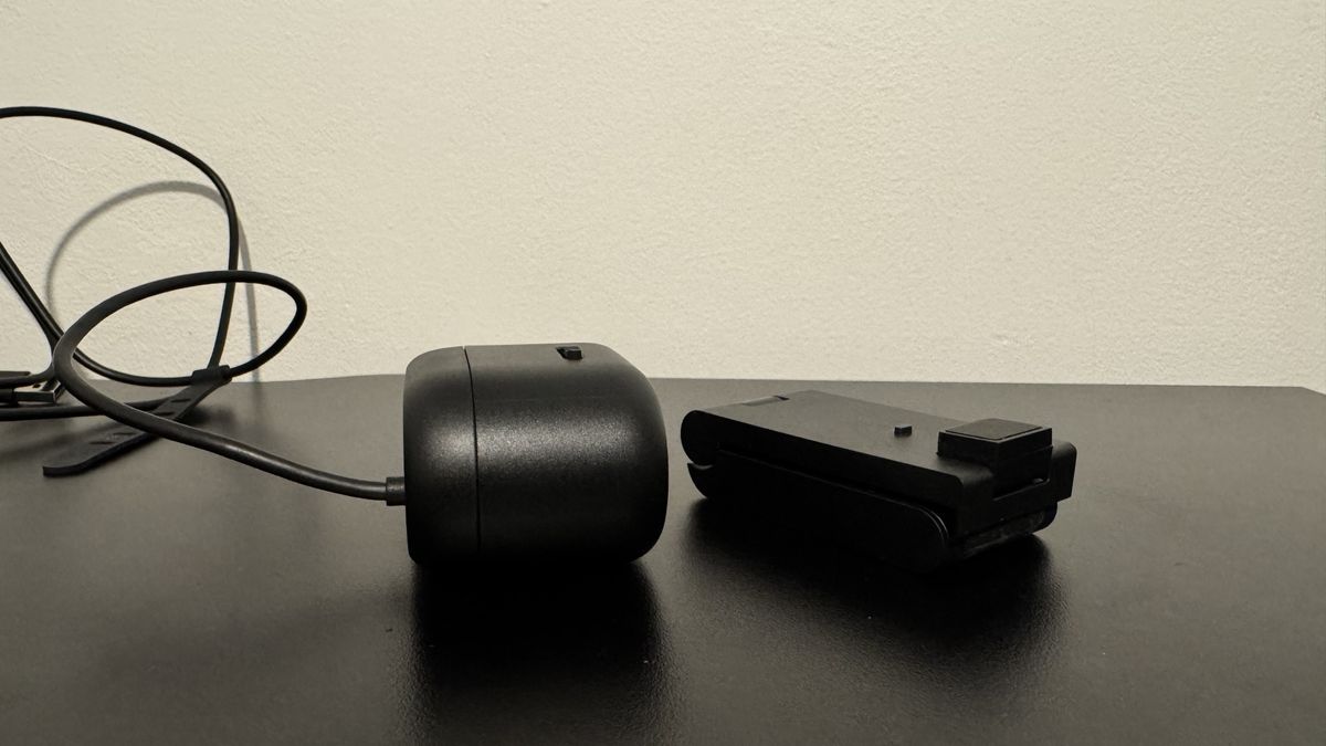 Dell Pro 5 webcam next to its stand on top of a black table