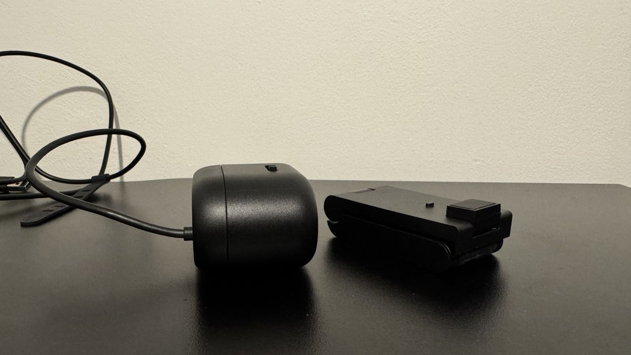 Dell Pro 5 webcam next to its stand on top of a black table
