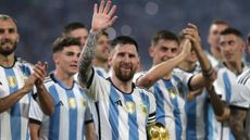 An image of Lionel Messi holding the World Cup while waving to fans, surrounded by his Argentina teammates 