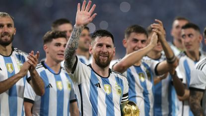 An image of Lionel Messi holding the World Cup while waving to fans, surrounded by his Argentina teammates 
