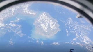 a view of a large island, seen through the window of an orbiting space station