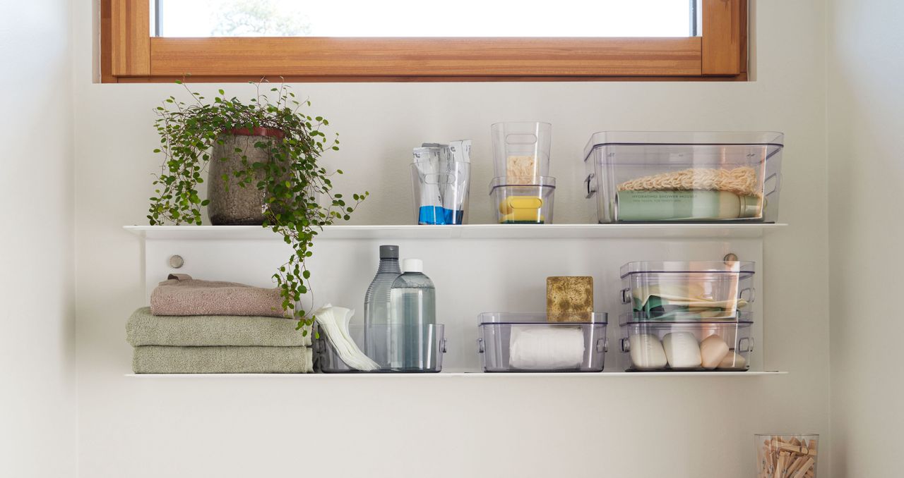 plastic boxes with bathroom things on two open shelves 