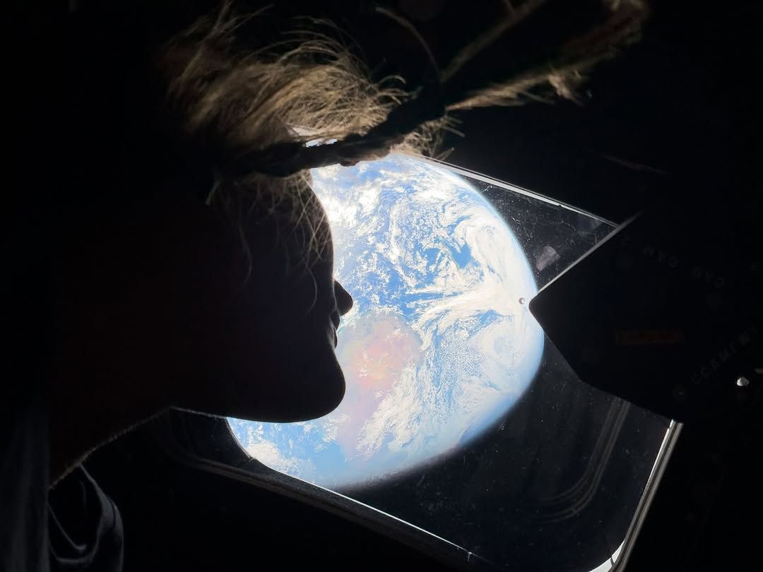 Artemis 2 astronaut Chistina Koch's shadow as she looks out the window at Earth/