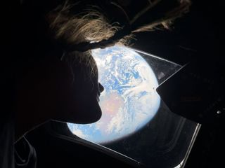 Artemis 2 astronaut Chistina Koch's silhouette as she looks out the window at Earth/