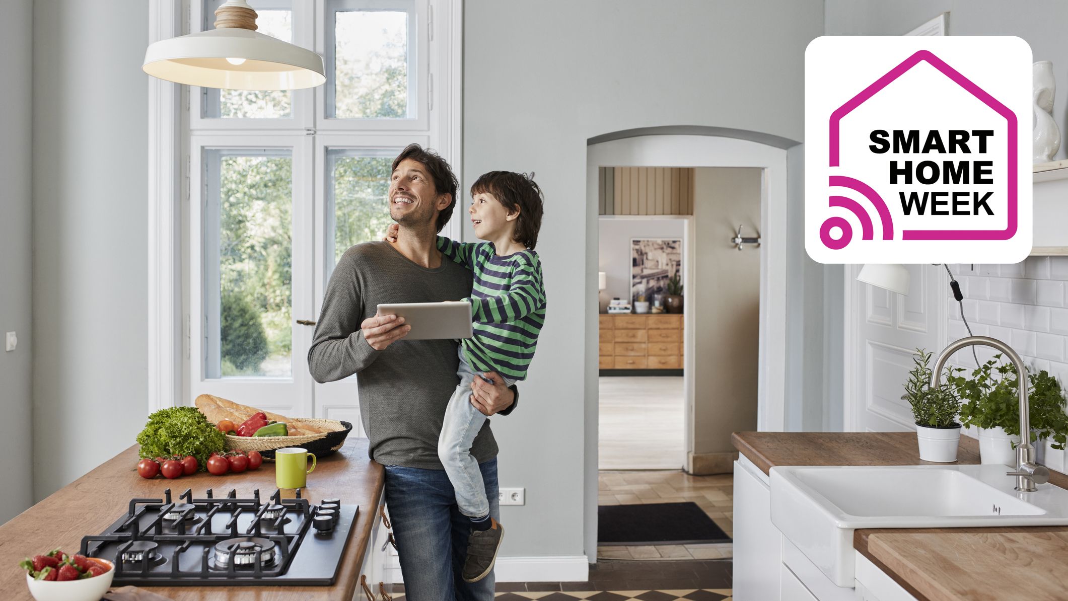 Man using tablet to control smart lights in kitchen while holding child