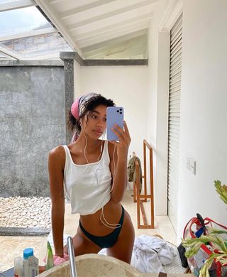 woman wearing silk headscarf and bikini bottoms with white tank