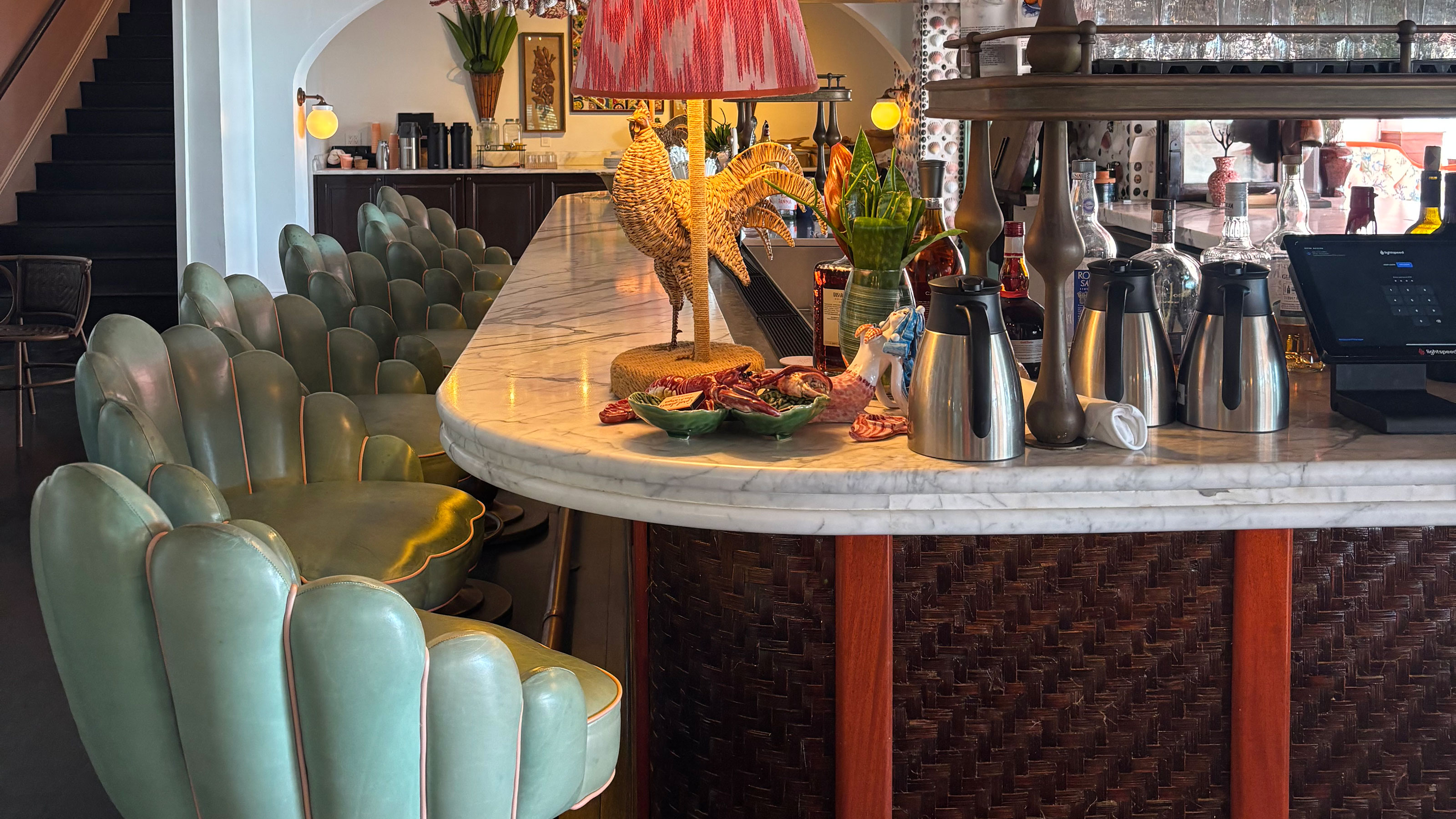 Marble topped bar with rounded corners surrounded by scalloped mint green bar stools