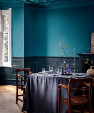 dining room with dark teal walls and ceiling and dark blue panelled wall