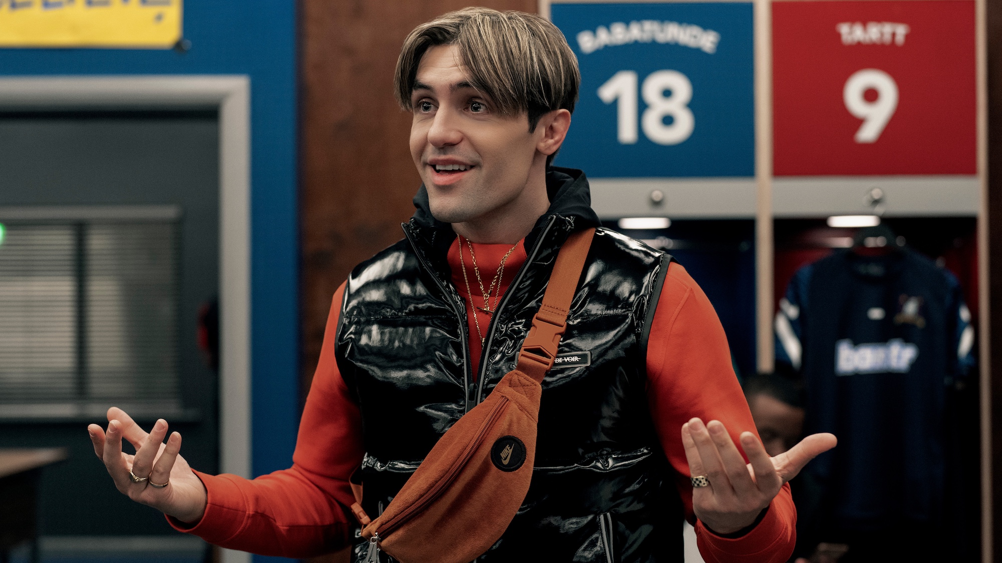 Phil Dunster in a puffer jacket and side purse in Ted Lasso