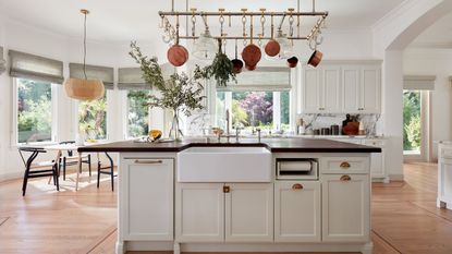 kitchen with white cabinets and hanging pans over island with black countertop
