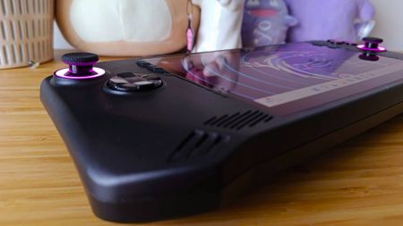 Angled view of black MSI Claw handheld on woodgrain unit with purple RGB sticks.