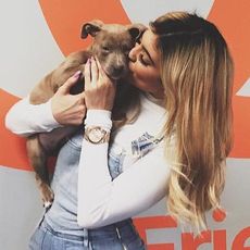 Kylie Jenner holds a puppy to her face and kisses its head.