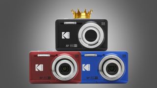 Three Kodak PixPro FZ55 compact cameras in red, blue, and black arranged in a stack, with a gold crown above the black camera against a gray backdrop