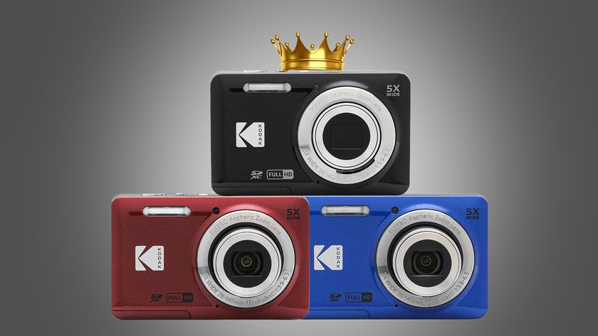 Three Kodak PixPro FZ55 compact cameras in red, blue, and black arranged in a stack, with a gold crown above the black camera against a gray backdrop