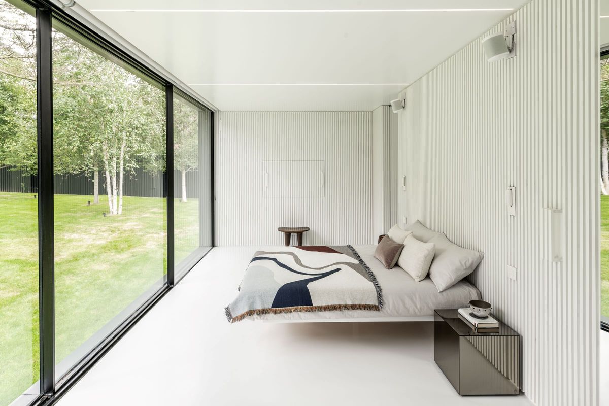 Inside the bedroom is a white room with panelled walls and floor to ceiling windows