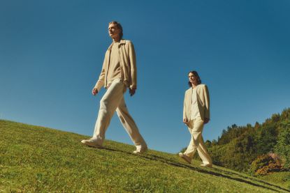 Two people walking in field wearing outfits by Zegna