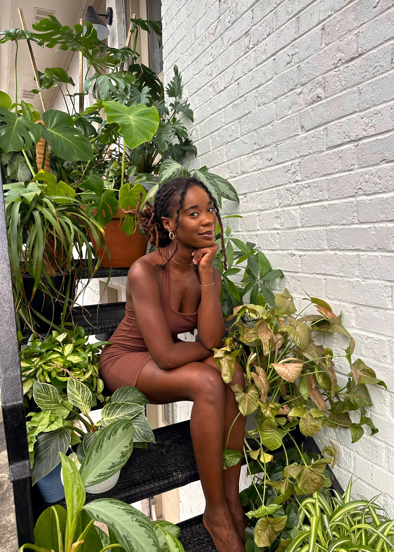 Paige Tailyn on a staircase dotted with potted houseplants