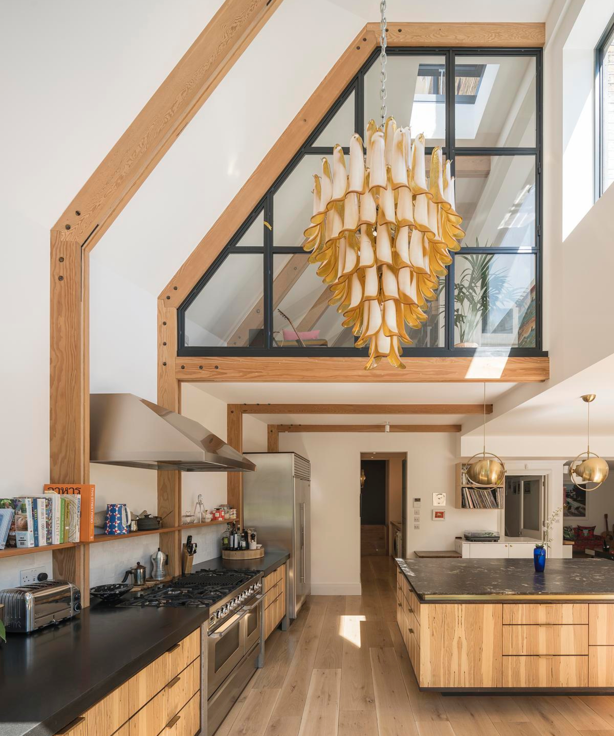 kitchen extension on victorian house with vaulted ceiling, large crital style internal window overlooking kitchen, wooden structural beams left exposed as design feature, modern wooden kitchen with black granite worktops