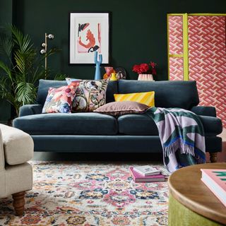 Green living room with blue velvet sofa and patterned rug