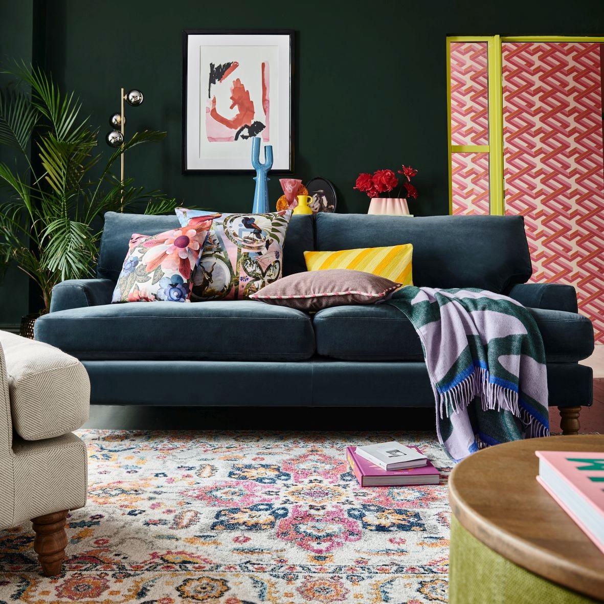 Green living room with blue velvet sofa and patterned rug