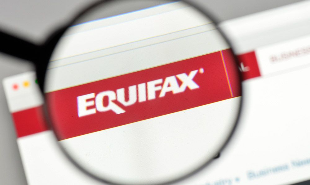 The Equifax logo under a magnifying glass.