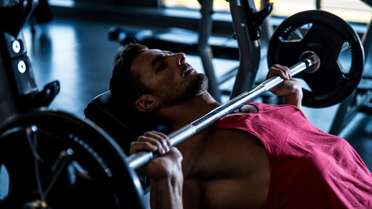 Person performing the bench press exercise in a gym