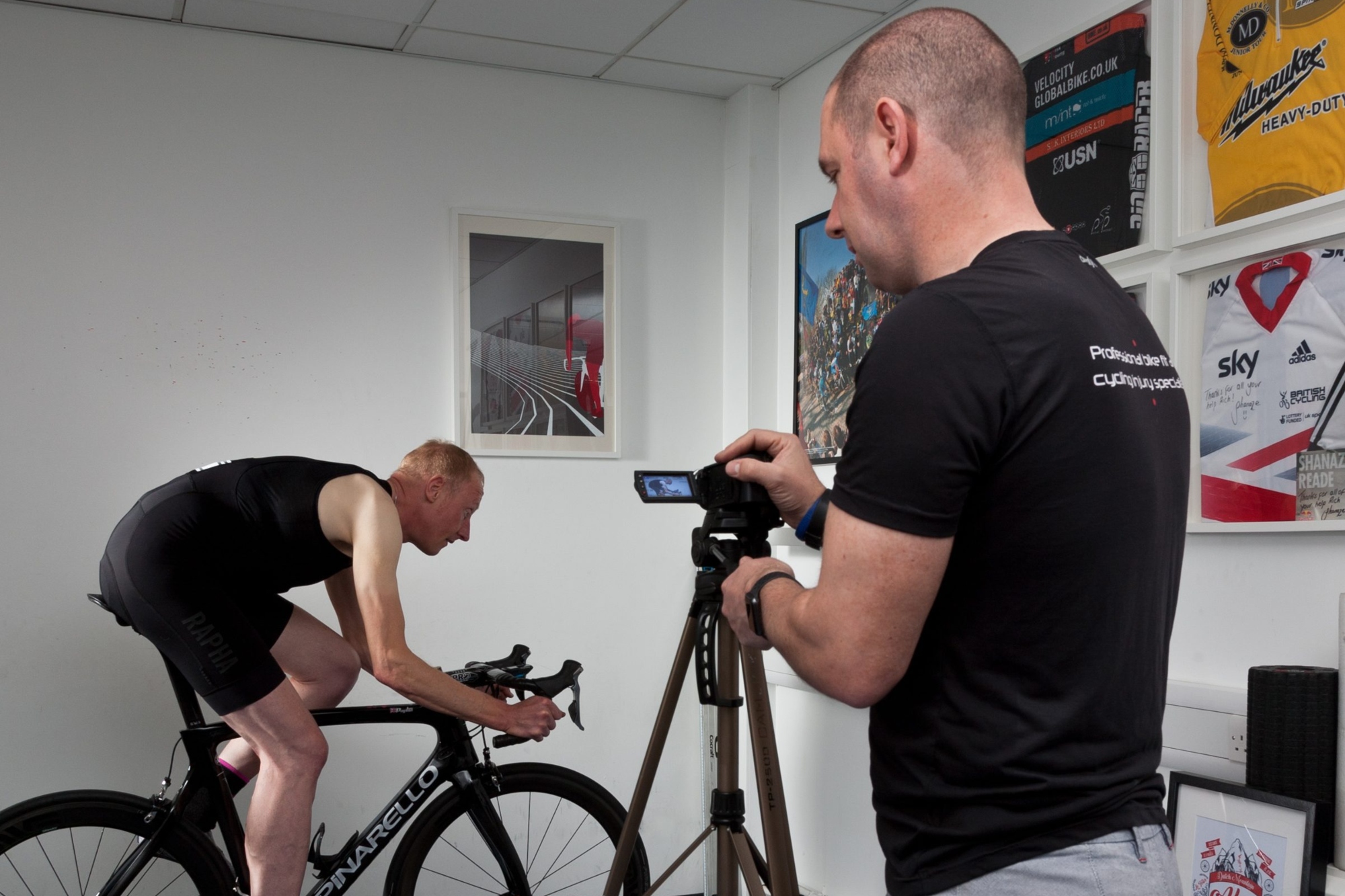Richard Salisbury from Pedal Precision with a camera monitoring a white man on a bike in a room