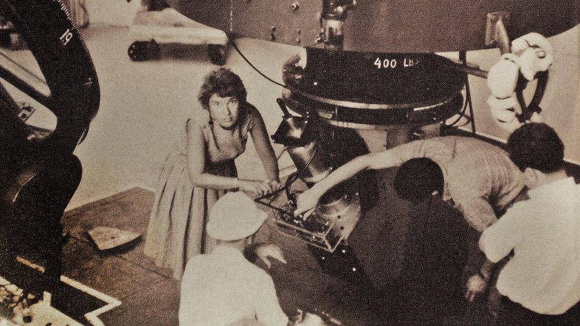 A sepia image of a woman working on a telescope.