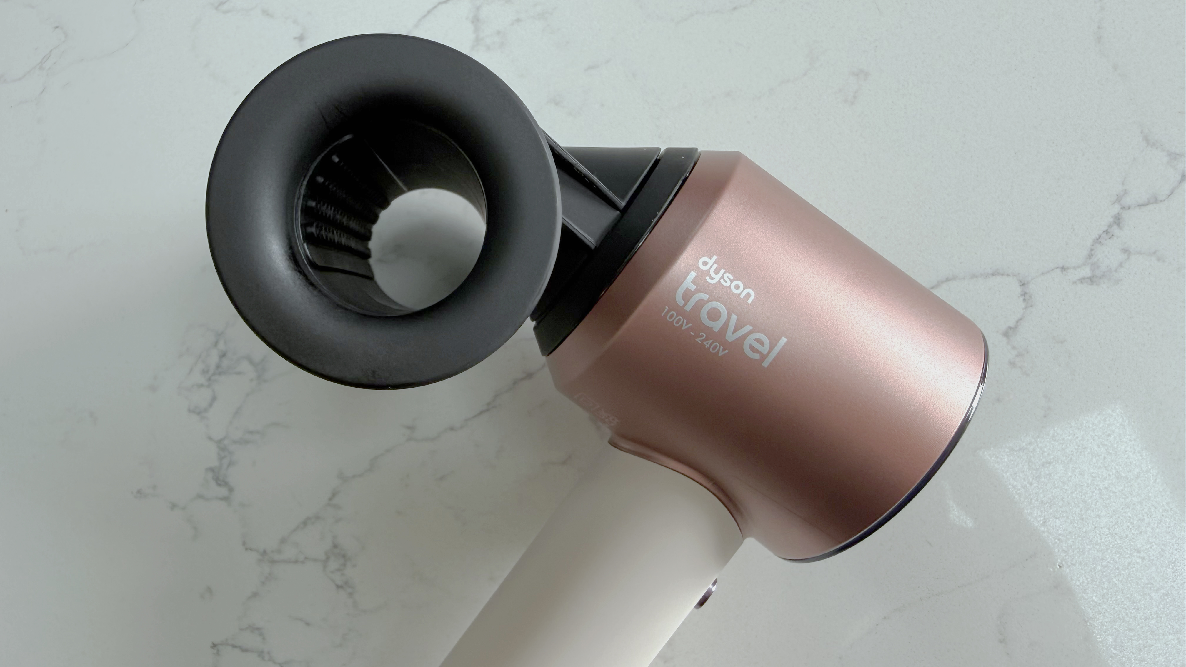 Dyson Supersonic Travel hair dryer beside a Dyson Nural styling attachment