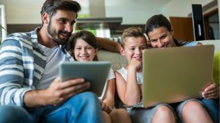 Parents reading to children from a tablet and laptop