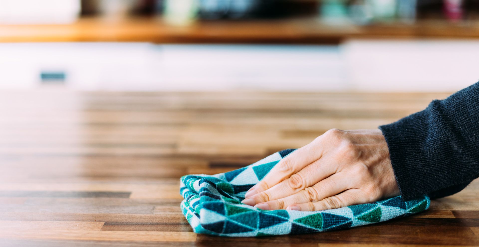 person wiping kitchen countertops as step for cleaning a kitchen