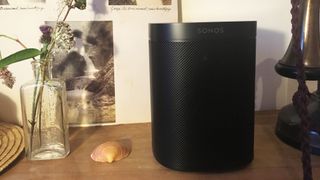 The Sonos One smart speaker in black on a wooden shelf