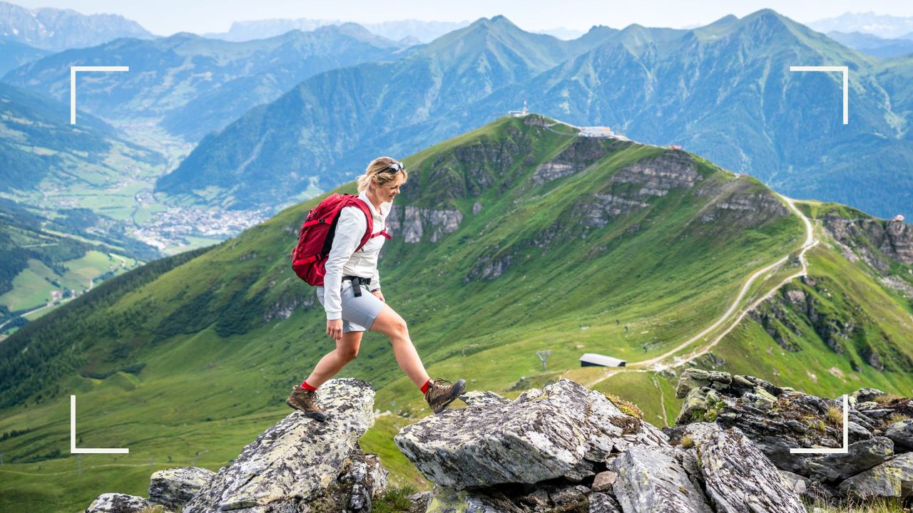 Woman hiking across rocks with mountains in the background, representing one of the many walking holidays in the UK