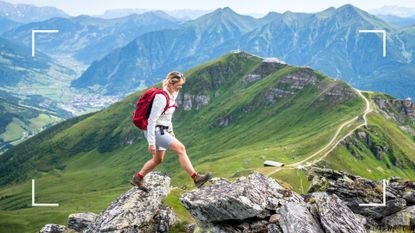 Woman hiking across rocks with mountains in the background, representing one of the many walking holidays in the UK