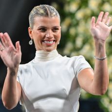a white woman in a white dress waving to a crowd